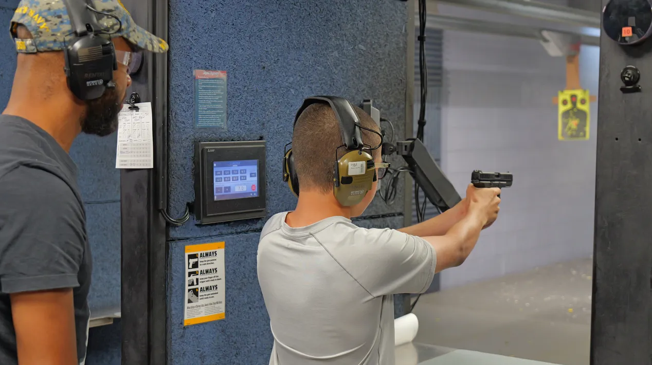 Shooter firing a rental handgun in a lane at Shoot Indoors